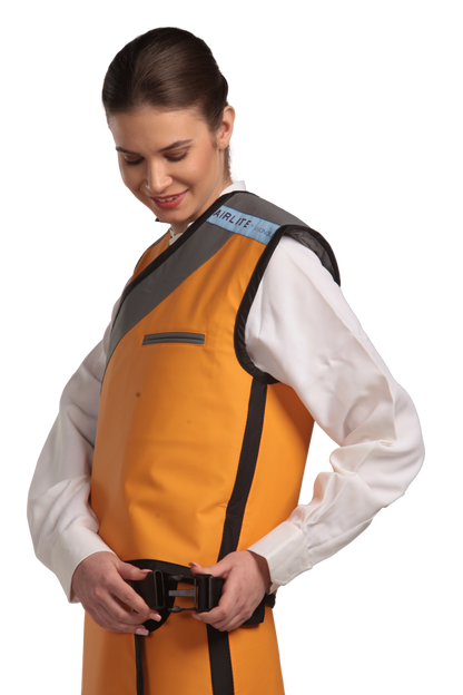 Side view of a female model wearing a tangerine radiation protection skirt and vest. The vest is tangerine with grey lines around the left edge and paracord buckles that fastens by the side. 