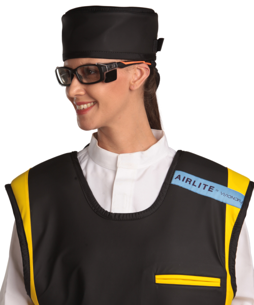 Up-close view of a female model wearing a radiation protection head shield, eyewear, and a coat apron. The apron is jet-black with yellow-colored lines by the edges.