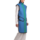 Frontal right-side view of a female model wearing a coat apron with an integrated thyroid guard. The apron is royal blue in color with an ocean green center line and has velcro fasteners by the sides.