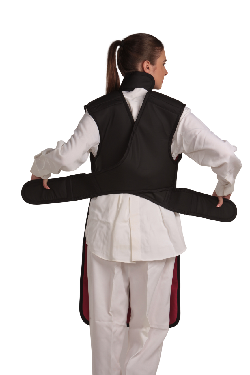 Back view of a female model wearing a coat apron with a flex back and an integrated thyroid guard. The apron is Jet black with a Bordeaux red center line and has unfastened velcro fasteners held in the model's hands. 