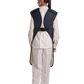 A rear view of a female model wearing a navy blue, beige-lined coat apron with flex back fastened.
