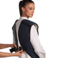 A partial back view of a female model wearing a navy blue, beige-lined coat apron with flex back. The paracord buckle is open and being fastened onto her back.