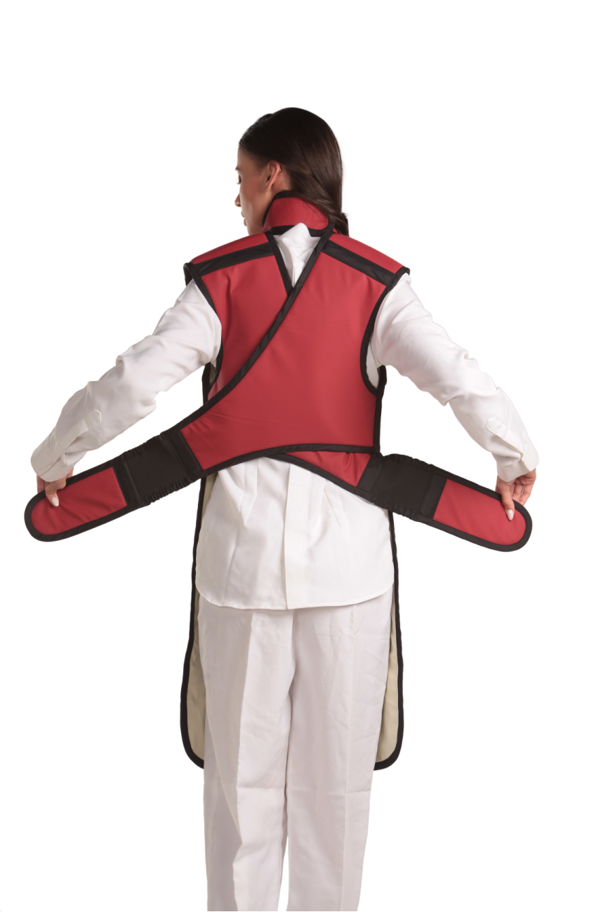 Back view of a female model wearing a coat apron with flex back and an integrated thyroid guard. The apron is Bordeaux red in color with a beige center line and has unfastened velcro fasteners held in the model's hands.