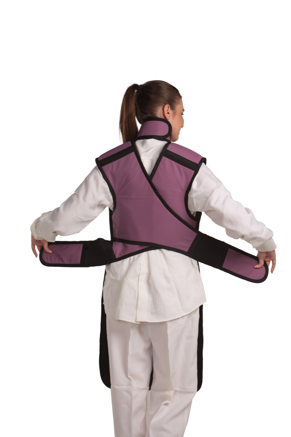 Back view of a female model wearing a coat apron with a flex back and an integrated thyroid guard. The apron is mauve in color with a Jet black center line and has unfastened velcro fasteners by the sides held in the model's hands.