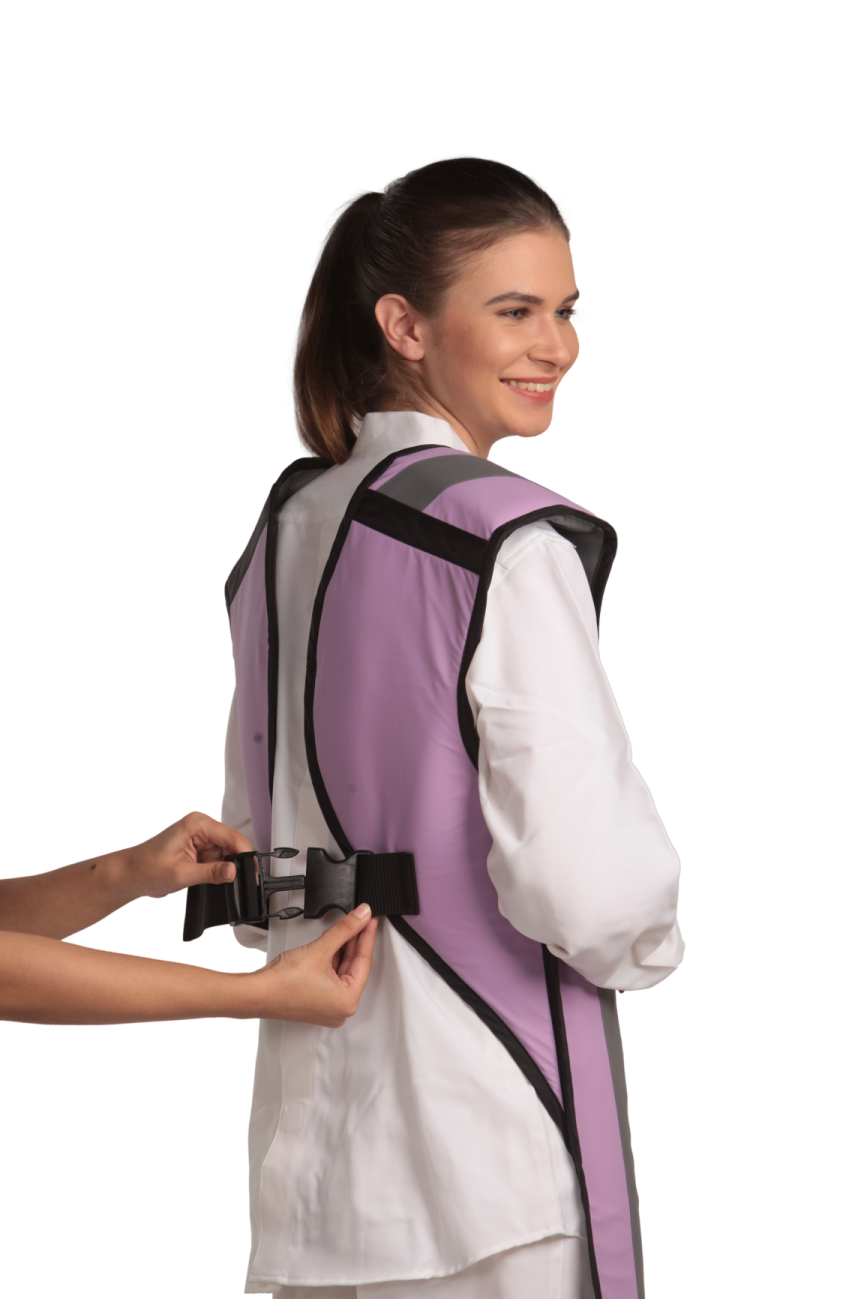 A partial rear view of a smiling female model wearing a lilac coat apron with flex back. The paracord buckle is open and being fastened onto her back. 